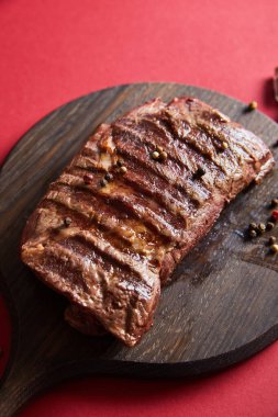 tasty grilled steak served on wooden boards on red background with pepper clipart