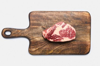 top view of fresh raw steak on wooden cutting board on white background clipart