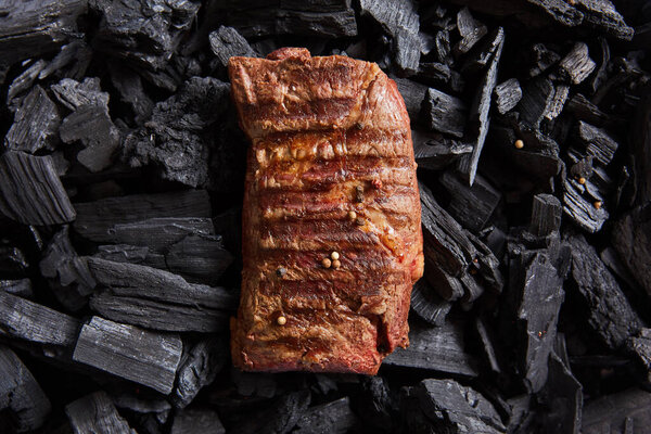 top view of fresh grilled tasty steak on black coals
