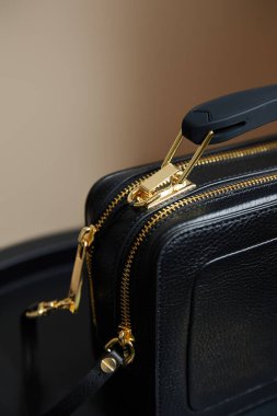Bej arka planda altın fermuarlı deri çantanın yakın görüntüsü
