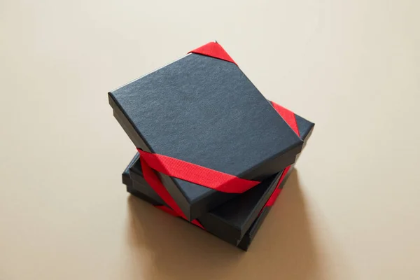 米色背景上有红丝带的黑色礼品盒 — 图库照片