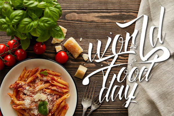 top view of tasty bolognese pasta with tomato sauce and Parmesan in white plate near ingredients and cutlery on wooden table, world food day illustration
