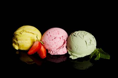 Lezzetli limon, çilek ve siyah üzerine izole edilmiş naneli dondurma topları.