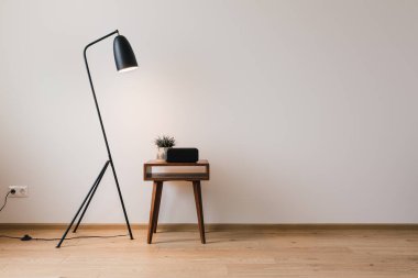 metal floor lamp and wooden coffee table with plant and clock with blank screen clipart