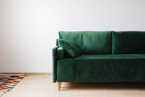 green sofa with pillow near colorful rug on floor