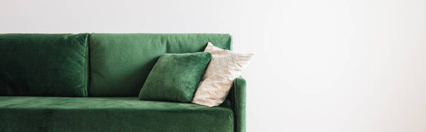 modern green sofa with pillows in spacious room near grey wall, panoramic shot