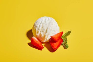 fresh tasty ice cream ball with mint leaves and strawberry on yellow background clipart