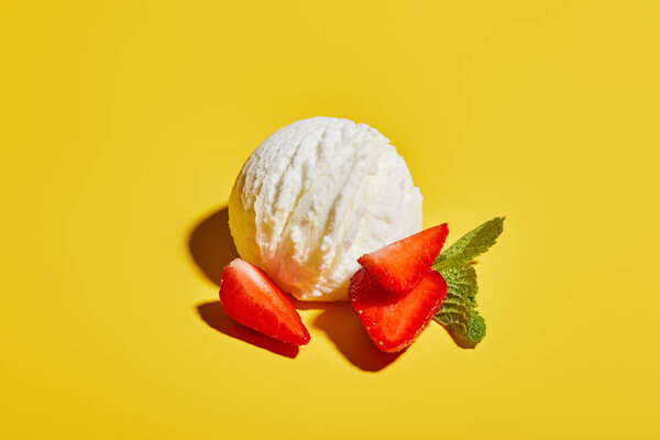 fresh tasty ice cream ball with mint leaves and strawberry on yellow background