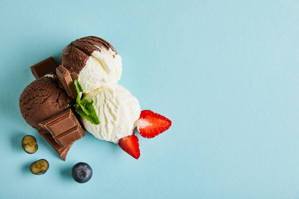 вид на вкусное коричневое и белое мороженое с ягодами, шоколадом и мятой на голубом фоне
