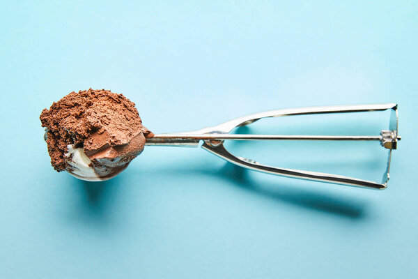 top view of fresh tasty chocolate ice cream ball in scoop on blue background