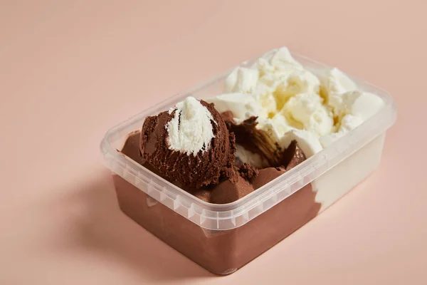 粉红背景塑料容器中美味的褐色和白色冰淇淋的选择焦点 — 图库照片