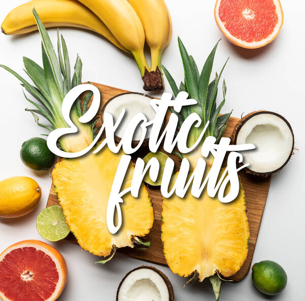 вид сверху на срезанные и целые экзотические фрукты на деревянной доске на белом фоне с иллюстрацией экзотических фруктов
