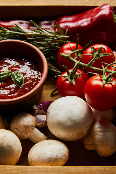 delicious tomato sauce in bowl near fresh ripe vegetables, rosemary and mushrooms