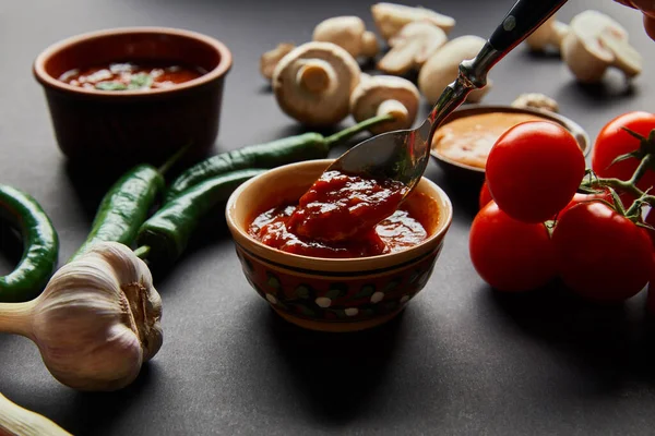 黒に熟した野菜の近くの赤いトマトソースのスプーンの選択的な焦点 — ストック写真