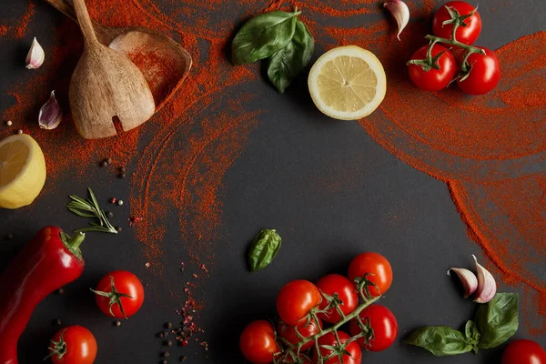 Top view of cherry tomatoes, garlic cloves, paprika powder, basil leaves and rosemary near lemons on black — Stock Image Top View Cherry Tomatoes Garlic Cloves Paprika Powder Basil Leaves Royalty Free Stock Images