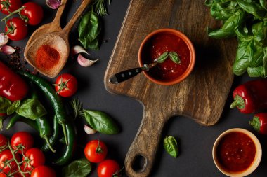 Kırmızı kiraz domatesleri, domates sosu, biberler, otlar ve siyah panonun yanında yeşil biberler.