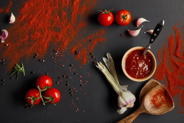 顶部的樱桃西红柿和新鲜的香草靠近勺子与红辣椒粉的黑色 — 图库照片
