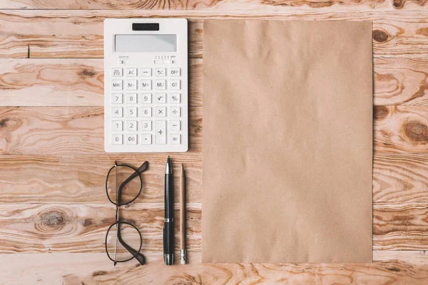 Калькулятор с очками и офисными принадлежностями на столешнице — стоковое фото