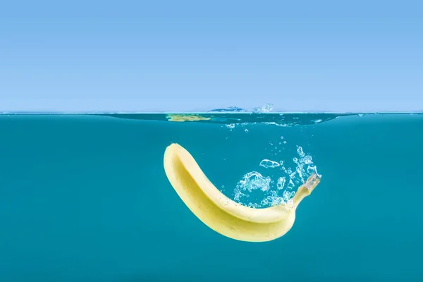 Banana galleggiante in acqua con bolle — Foto stock