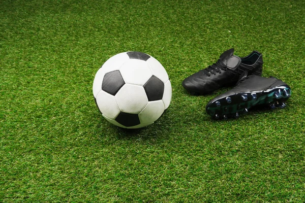 Pelota de fútbol con botas negras - foto de stock