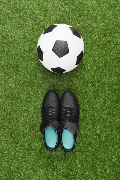 Pelota de fútbol con botas negras - foto de stock