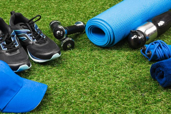 Fitness equipment and cap on green pitch — Stock Photo