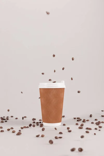 Taza desechable con granos de café - foto de stock
