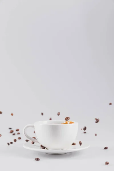 Tazza di caffè con chicchi di caffè sparsi — Foto stock