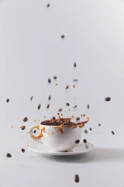 Tazza di caffè con grani di caffè cadenti — Foto stock