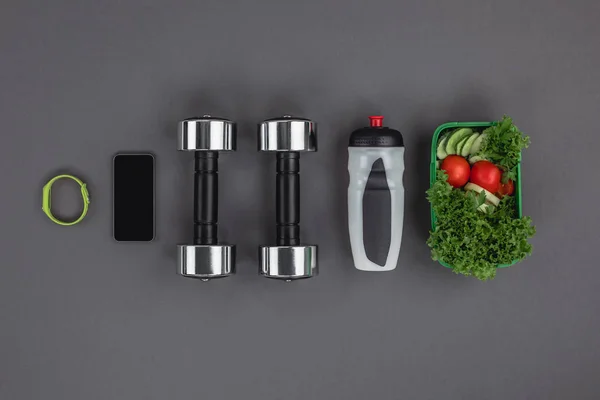 Dumbbells with vegetable salad and gadgets — Stock Photo