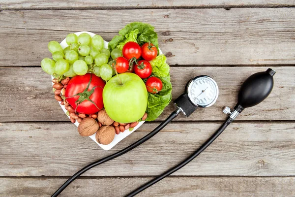 Verduras, frutas y medidor de presión arterial - foto de stock