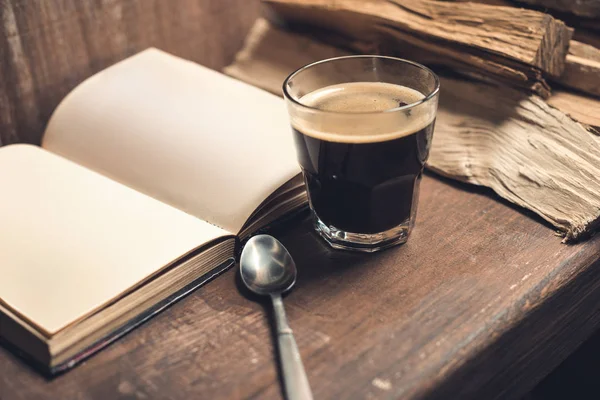 Un vaso de café, libro viejo - foto de stock