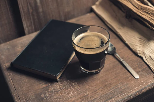 Un vaso de café, libro viejo - foto de stock