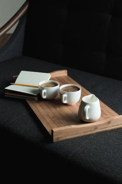 Coffee, jug of milk and notebook on tray — Stock Photo