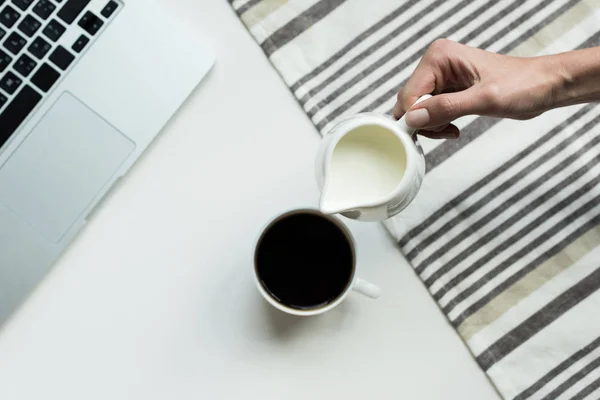 Verter leche en una taza de café negro - foto de stock