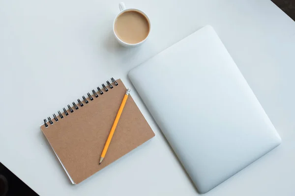 Ordenador portátil, bloc de notas y taza de café - foto de stock