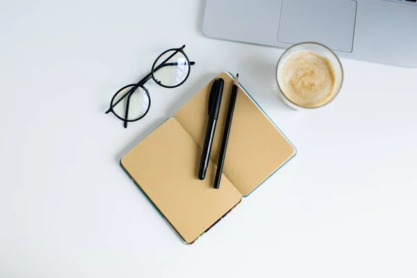 Portátil, bloc de notas y vaso de café - foto de stock