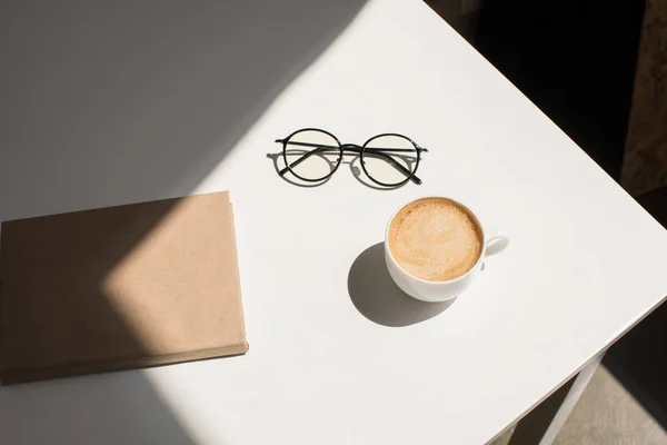 Taza de café, anteojos y bloc de notas - foto de stock