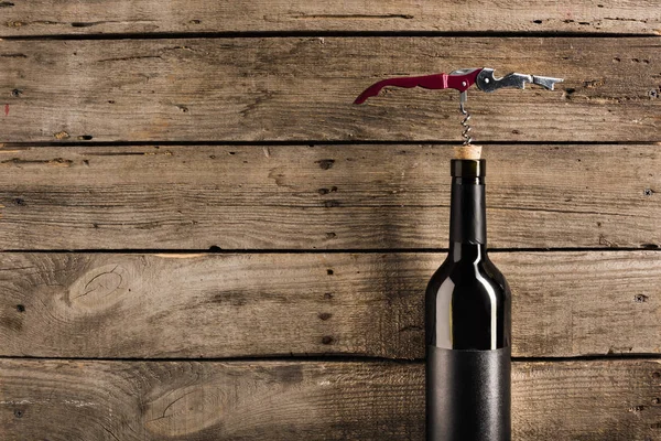Bottle of red wine and corkscrew — Stock Photo
