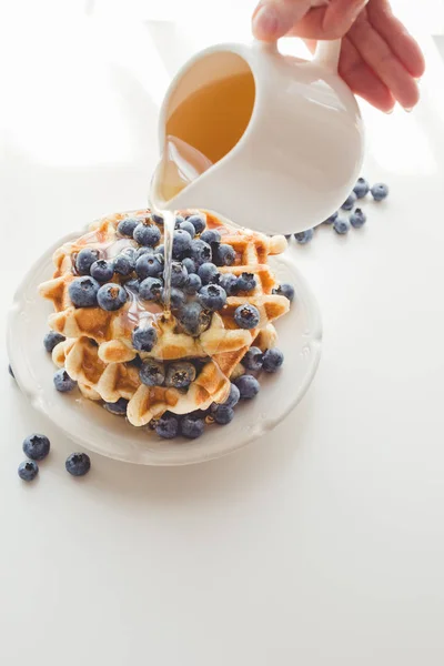 Woman pouring syrup on tasty waffles — Stock Photo