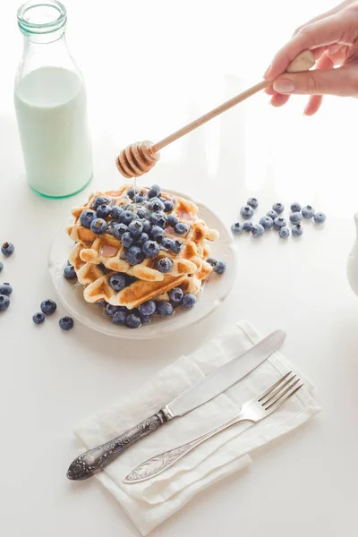 Mulher derramando mel em waffles saborosos — Fotografia de Stock