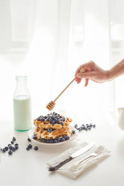 Mulher derramando mel em waffles saborosos — Fotografia de Stock