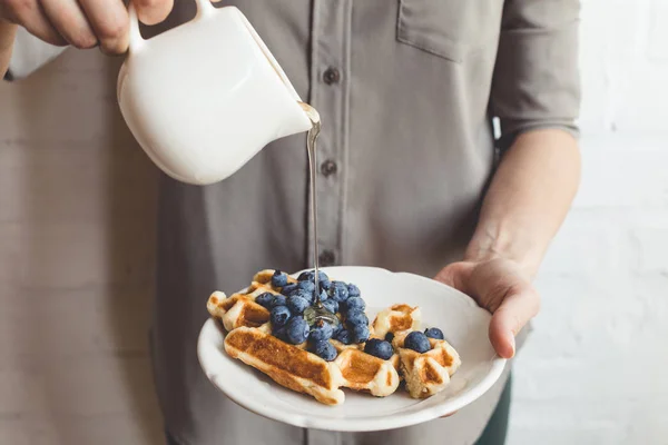 Woman pouring syrup on tasty waffles — Stock Photo