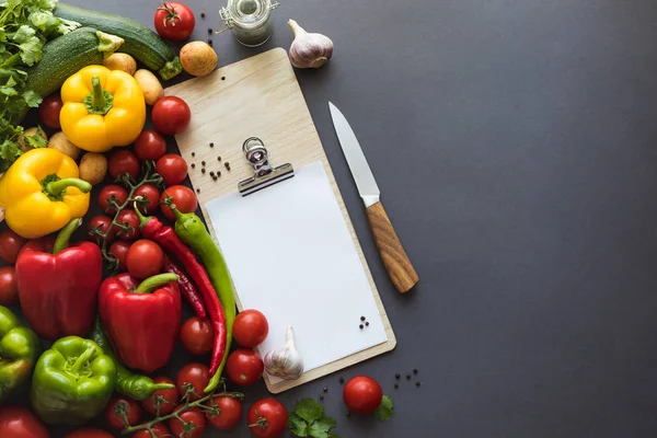 Verduras con papel en blanco y tabla de cortar - foto de stock