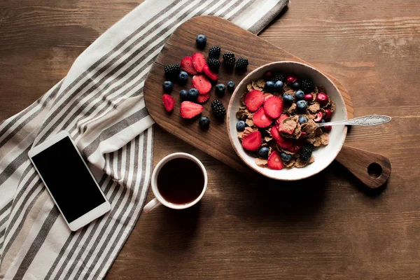 Flakes with berries and smartphone — Stock Photo