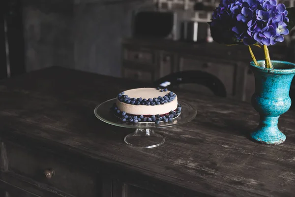 Cheesecake with blueberries on glass stand — Stock Photo