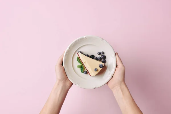 Woman holding slice of cheesecake — Stock Photo