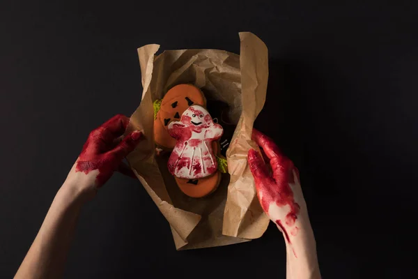 Mãos que embrulham biscoitos de Halloween — Fotografia de Stock