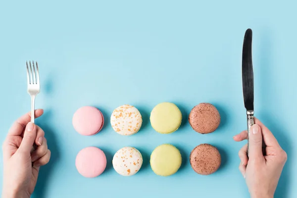 Macarons und weibliche Hände mit Silberbesteck — Stockfoto