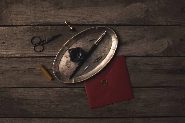 Plateau avec stylo encre et enveloppe rouge — Photo de stock